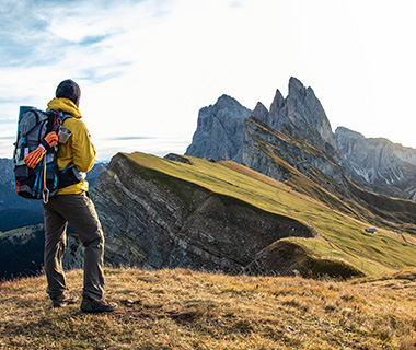 hiker in yellow jacket with backpack standing on mountain ridge overlooking stunning landscape of rocky peaks and valleys ideal for 15 adventures in nature